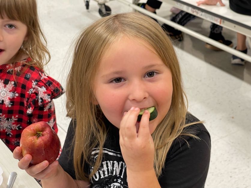 Student crunching into a slice of cucumber